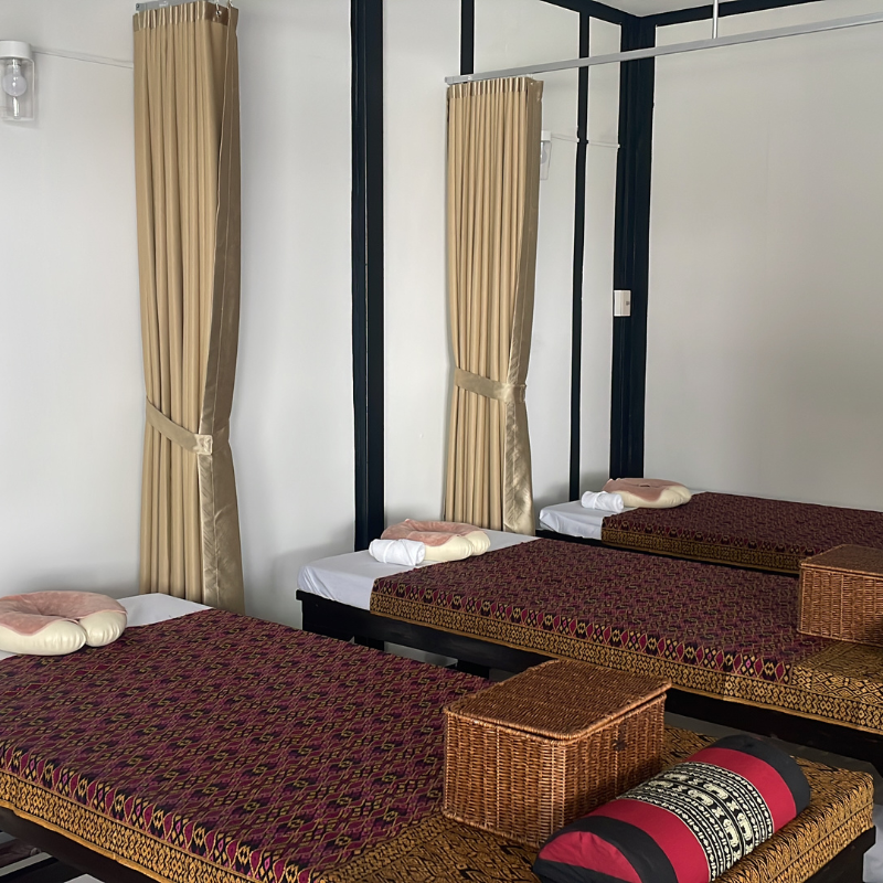 Row of traditional Thai massage beds with curtains in a private treatment room