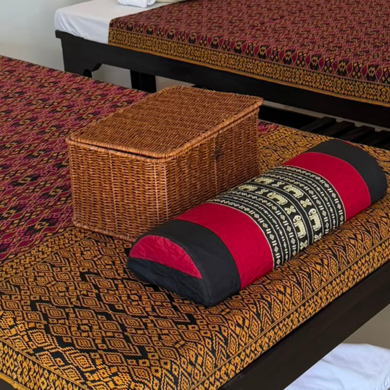 Thai bolster pillow and rattan box on a patterned massage bed
