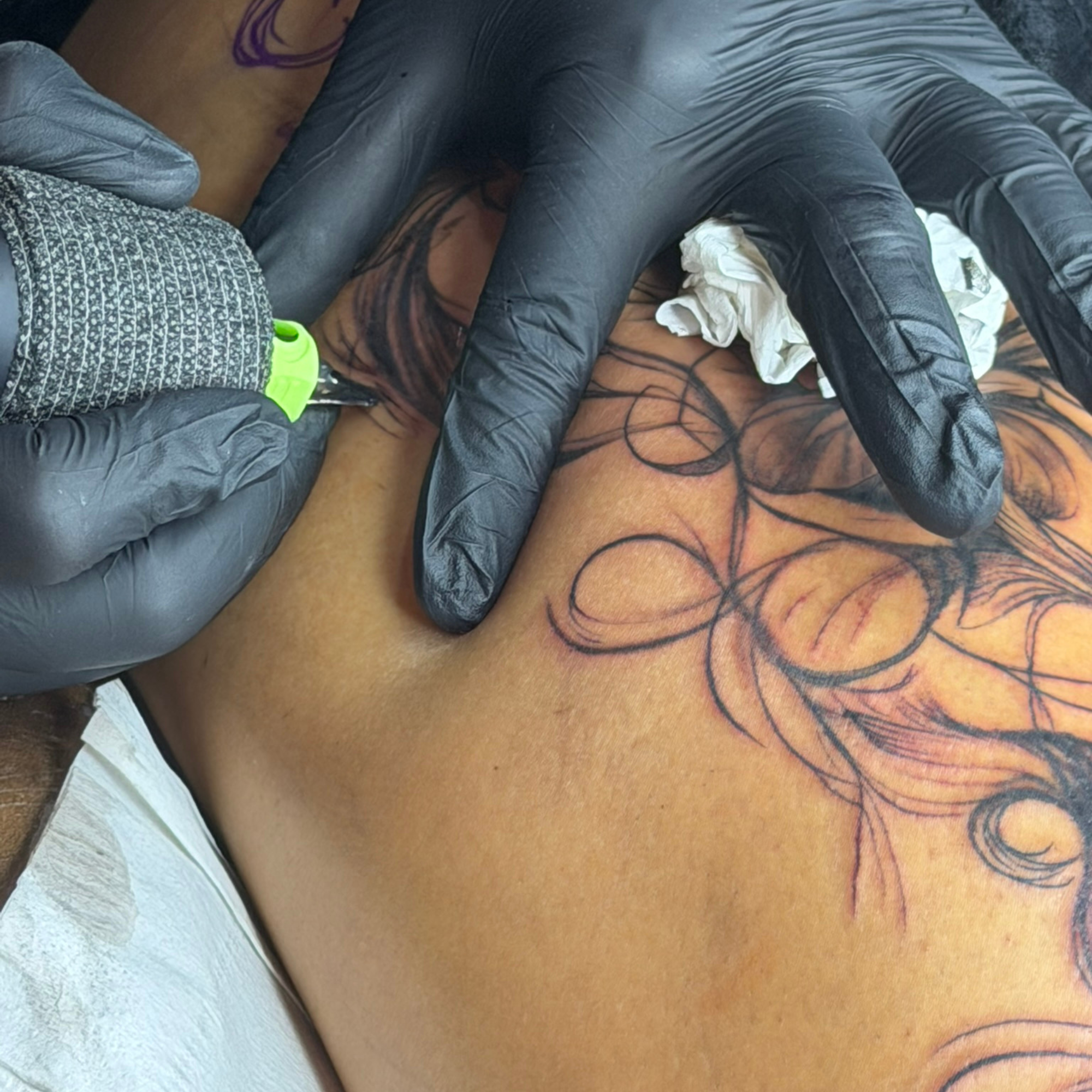 Tattoo artist inking a delicate floral line-work design in the studio