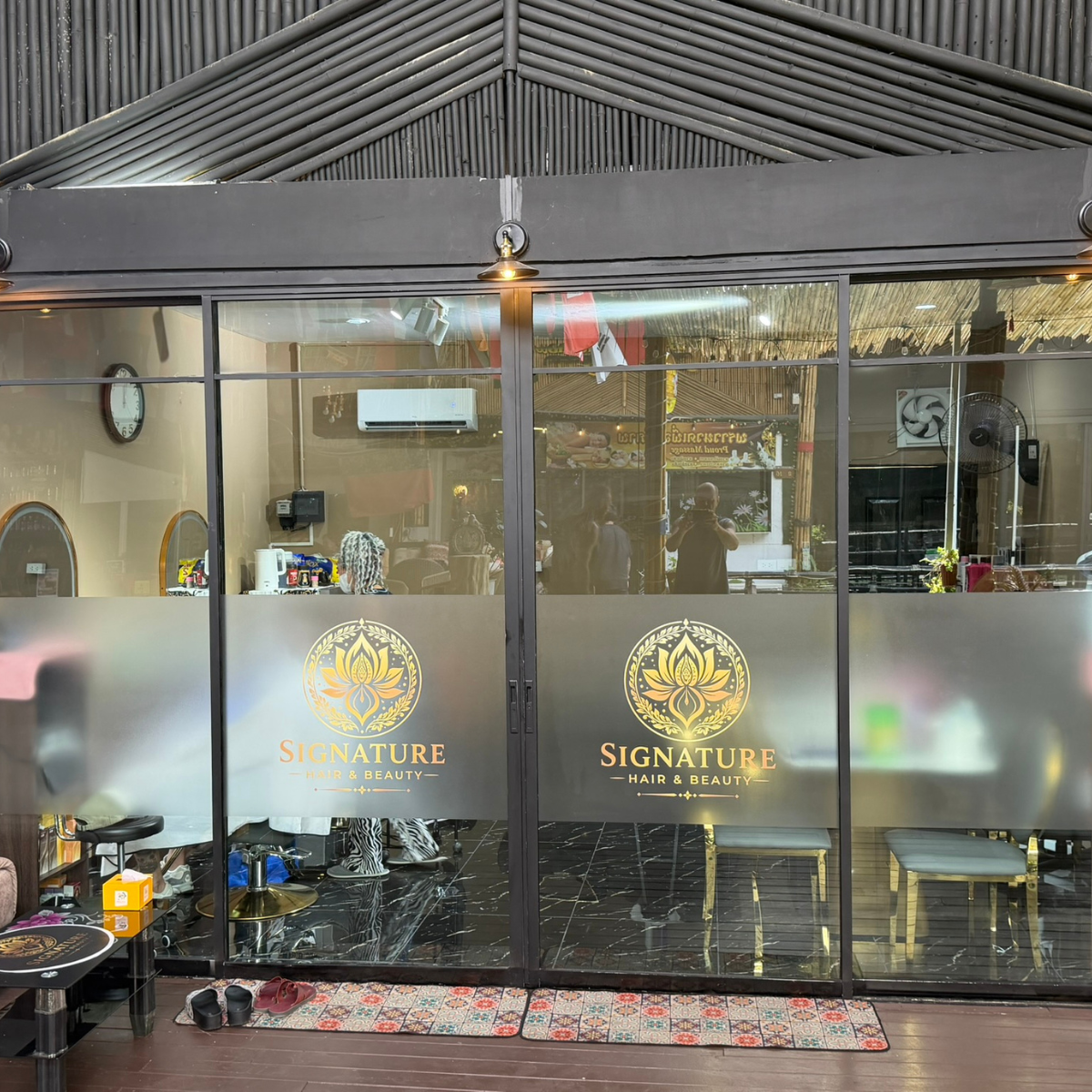 Front entrance of Signature Hair & Beauty with gold lotus logo on the glass doors