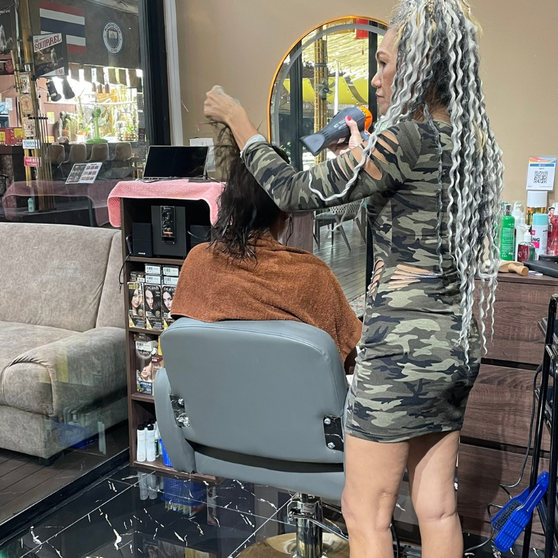 Stylist blow-drying a client's hair at the salon
